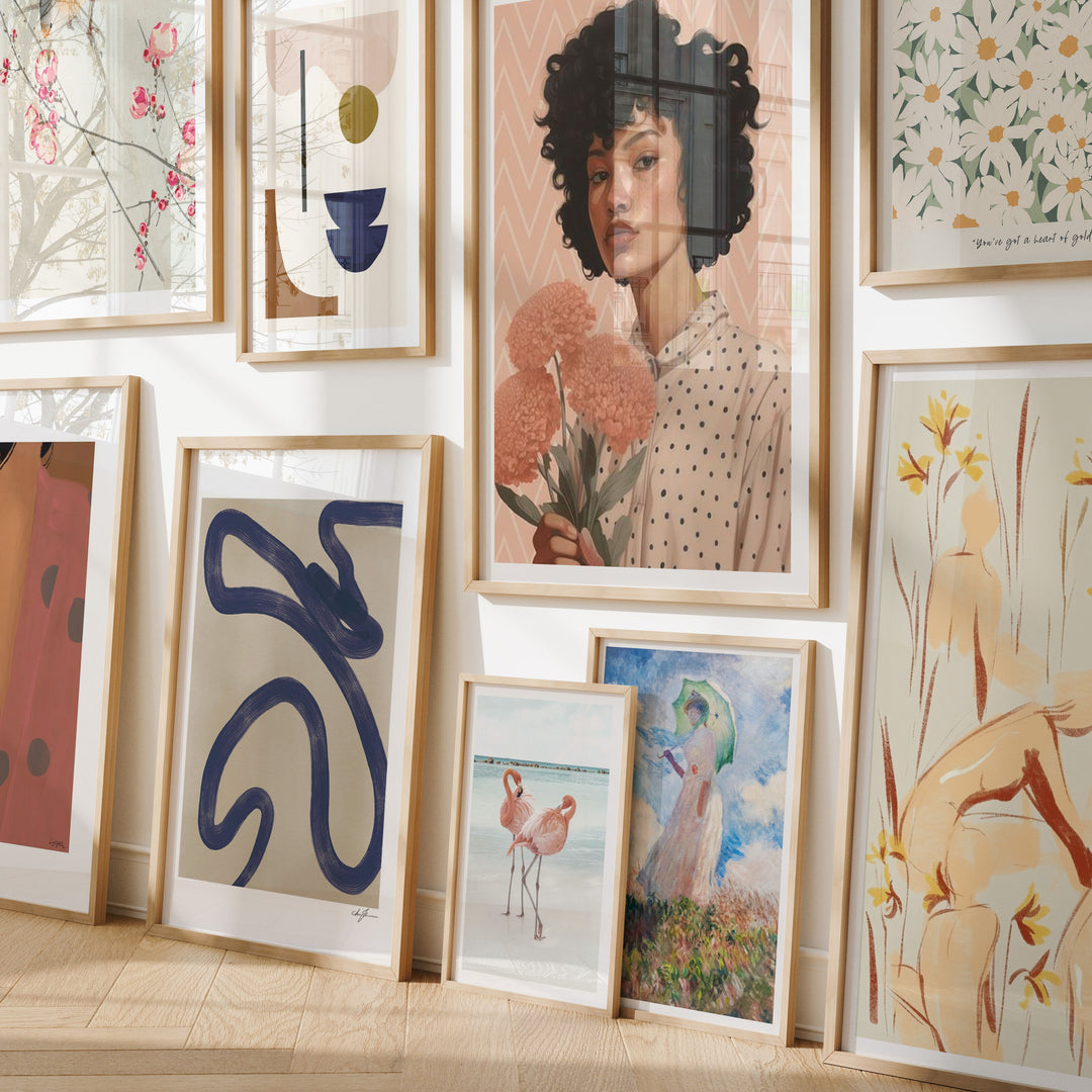 Wall with various framed artworks including abstract designs and portraits.