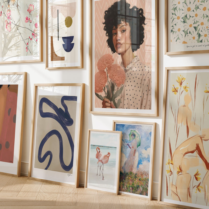 Wall with various framed artworks including abstract designs and portraits.